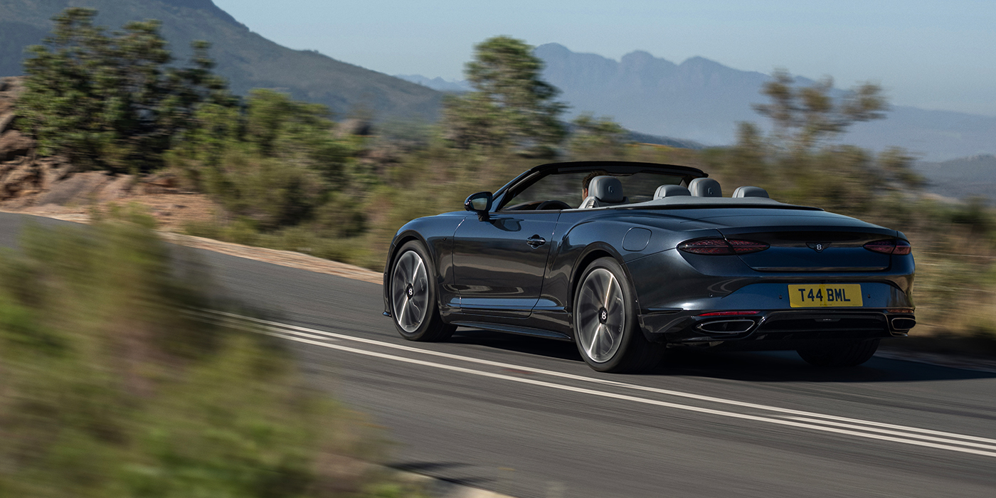 Bentley Düsseldorf Bentley Continental GTC S convertible in Thunder blue paint rear 3/4 driving on mountain road