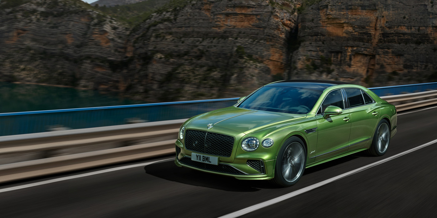 Bentley Düsseldorf Bentley New Flying Spur Speed v8 hybrid sedan driving dynamically on a mountain road in Tourmaline Green paint
