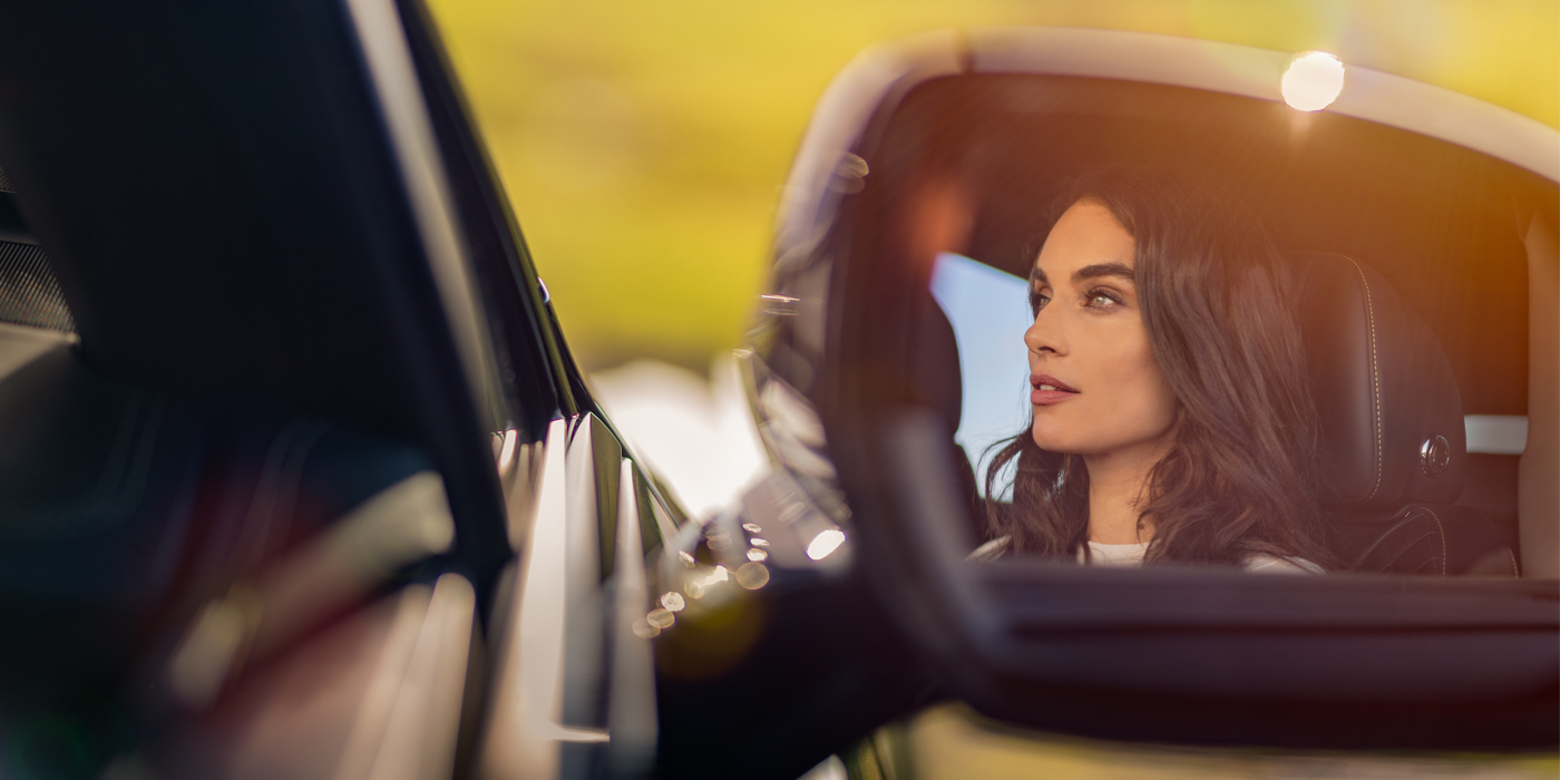 Bentley Düsseldorf profile of dark haired woman's face in mirror of Bentley car in sunlight
