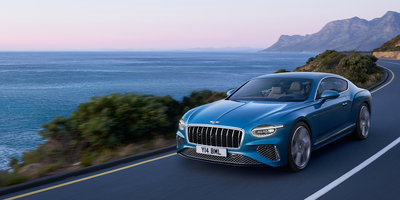 Bentley Düsseldorf New Bentley Continental GT Azure coupe in Light Windsor blue paint with 22 inch Azure wheels and chrome grill, driving dynamically by the sea