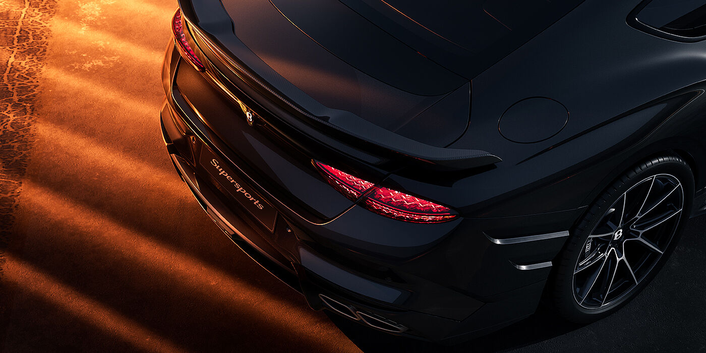 Bentley Düsseldorf Bentley Supersports rear overhead view showing illuminated rear lamps and Supersports Forged Alloy wheel in Anthracite paint against a dark grey and red background