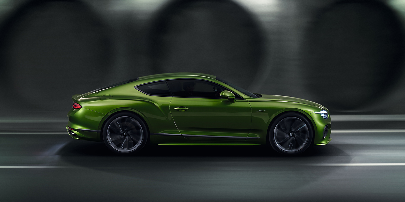Bentley Düsseldorf Bentley Continental GT coupe in Tourmaline Green paint driving in profile on a dark road